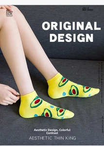Detail of yellow cotton low-cut sock with avocado pattern and blue polka dots on a model