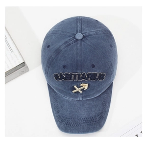 Detail of blue washed cotton baseball cap with Sagittarius embroidery and gold arrow symbol