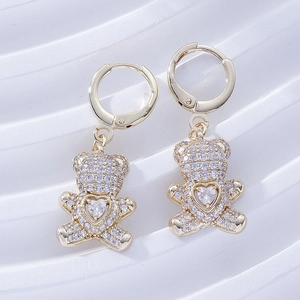 Macro view of gold teddy bear earrings with pavé zircons and heart-shaped center stone