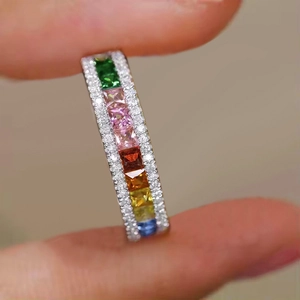 Macro shot of colorful square-cut zircon stones on a silver rainbow eternity ring band