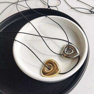 Detailed close-up of hollow heart pendants in gold and silver finish with black cords