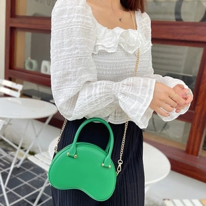 Stylish green PVC jelly handbag for women with gold chain strap in outdoor setting