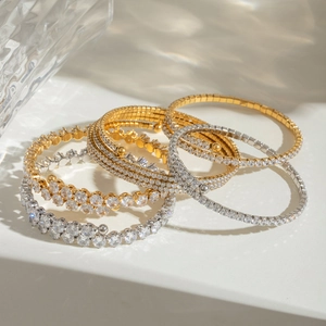 Close-up of stacked gold and silver stainless steel bangles with sparkling zircon stones