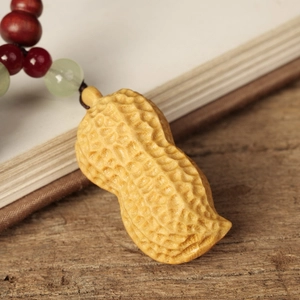 Detailed view of hand-carved sandalwood peanut pendant with colorful beads on wooden surface