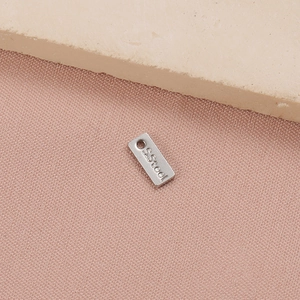 Macro shot of rectangular stainless steel charm with S.Steel engraving for DIY jewelry