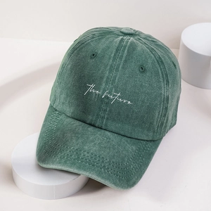 Vintage washed green baseball cap with white The Future embroidery on a minimalist stand