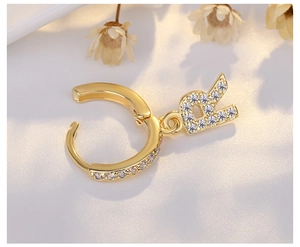 Macro shot of gold letter R huggie hoop earring with sparkling micro-pave crystals