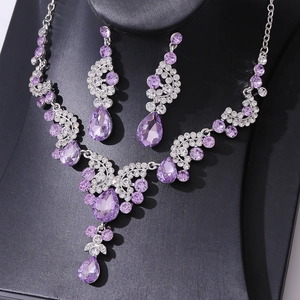 Elegant silver jewelry set with purple pear-cut crystals on a black display stand