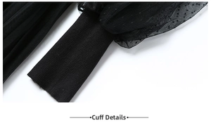 Detailed view of black ribbed cuffs and polka dot mesh sleeve on the knitted dress