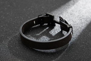 Détail d'un bracelet en cuir tressé noir avec fermoir ancre en acier sur surface sombre