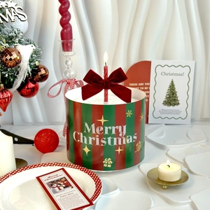 Burgundy velvet bow on striped Merry Christmas cake topper with a lit red candle
