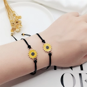 Close-up of two adjustable sunflower charms on black braided bracelets for mother and daughter