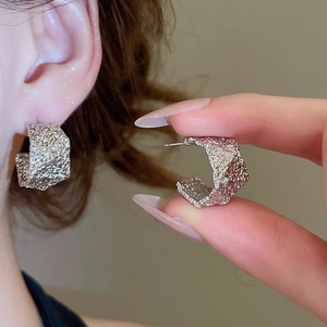 Detail shot of silver C-shaped earrings with unique irregular hammered texture on model