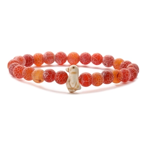 Close-up of orange dragon-vein agate beaded bracelet with a small penguin charm