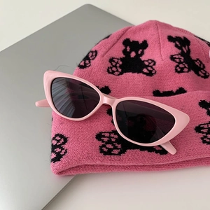 Detailed view of pink cat eye sunglasses on a pink knitted beanie with a bear motif