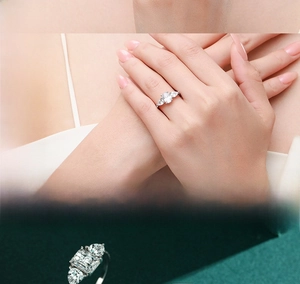 Macro detail of oval cut faux diamond engagement ring on dark green velvet background