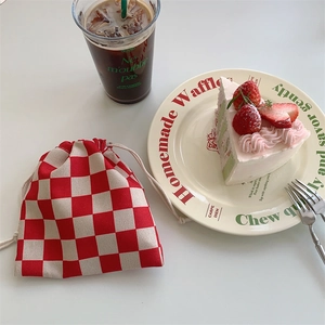 Detalle de la bolsa de punto a cuadros rojos y crema con textura de algodón grueso