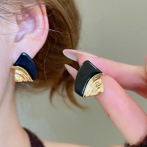 Macro view of geometric fan-shaped earrings with black enamel and 18k gold plating details