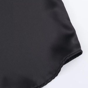 Detail shot of the black satin blouse showing curved hem and smooth silk-like texture