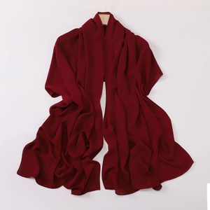 Detail of red chiffon shawl showing soft drape and lightweight texture on wooden hanger