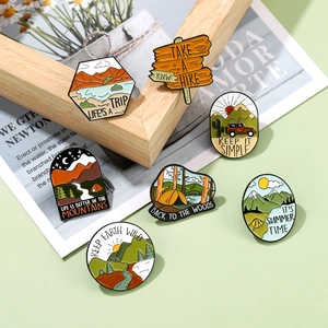 Detailed close-up of colorful outdoor camping enamel pins on a natural wood background