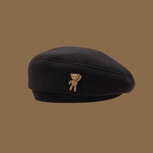 Classic black wool beret featuring a cute brown 3D bear accessory on a flat background
