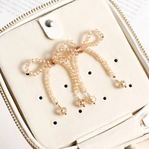 Close-up of handmade beaded bow earrings with champagne crystal tassels on jewelry box