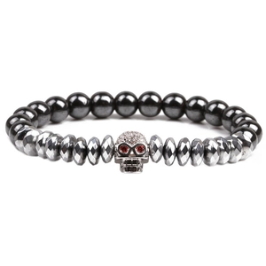 Close-up of beaded stone bracelet with metallic skull charm and red crystal eyes