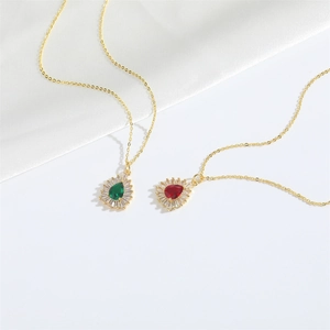 Detail of red and green pear-shaped gemstone pendants with gold chain on white silk