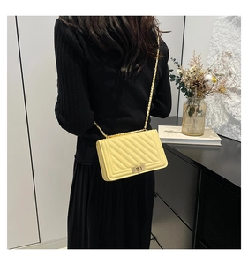 Close-up of a yellow quilted handbag with a gold chain strap and square clasp detail