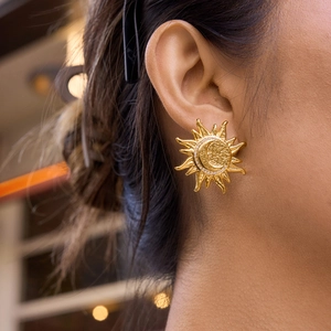 Detailed close-up of a sun and moon gold stud earring with sparkling crystals on a model