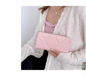 Pink long zip-around purse with quilted geometric pattern held by a model