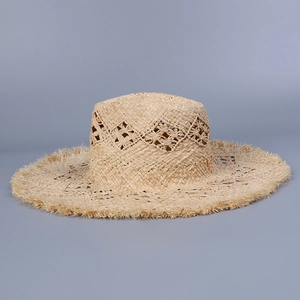 Detailed close-up of handmade raffia sun hat featuring hollow diamond weave and frayed edges