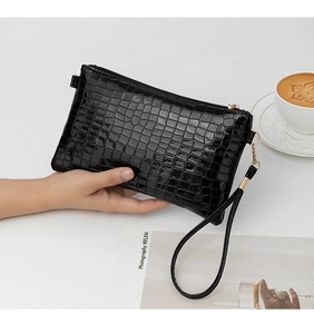 Close-up of black crocodile embossed clutch bag with sleek gold-tone hardware.