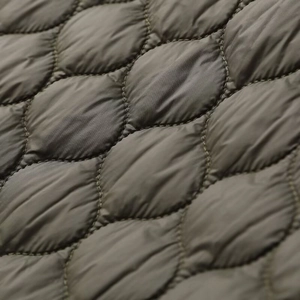 Macro shot of olive quilted nylon fabric showing high-density stitching and puffed texture