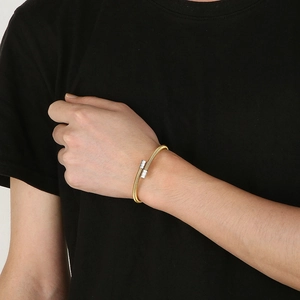 Close-up of golden stainless steel cable twist bracelet with silver end accents on wrist
