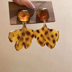 Gros plan de boucles d'oreilles en acrylique ambré avec détails de feuilles de ginkgo