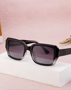 Detail view of bold square-frame sunglasses with gradient lenses on a minimalist pedestal