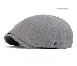 Détail d'un béret gris foncé montrant la texture en coton-lin et un badge métallique rétro