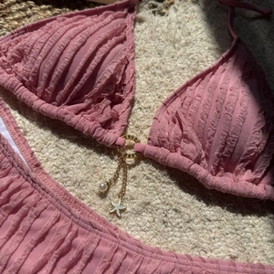 Close-up of pink bikini textured fabric with starfish pendant and gold ring detail