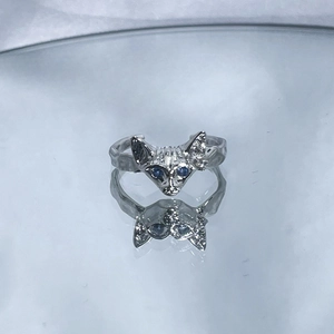 Detailed close-up of a silver cat-shaped ring with blue gem eyes and irregular texture