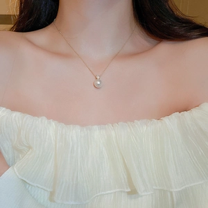 Close-up of elegant gold chain necklace featuring a single pearl and zircon accents on model