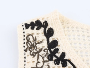 Detail of bohemian crochet vest featuring hollow-out knit and black floral embroidery