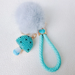 Blue mushroom keychain with rhinestones, fluffy pom-pom, and woven leather strap