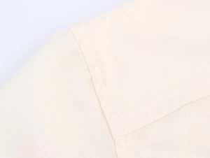 Gros plan sur la texture du tissu blanc cassé et les coutures précises de l'ensemble