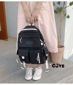 Detail of black nylon backpack featuring white contrast buckles and multiple zipper pockets