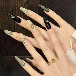 Detail of luxury long almond press-on nails with black rose art and gold glitter