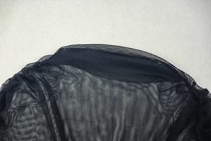 Detail of sheer black mesh fabric layers with reinforced edges on a sleek bodycon dress