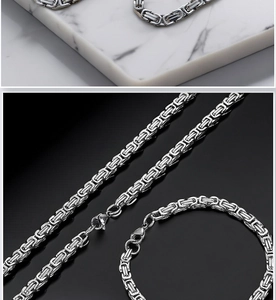 Detailed view of silver Byzantine chain necklace and bracelet on marble and dark background
