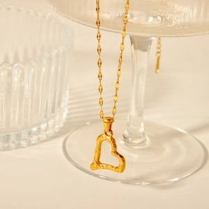 Close-up of a 18K gold heart pendant with irregular texture on a fine chain